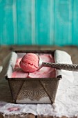 Cranberry sorbet in an ice cream container with an ice cream scoop
