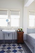 Bathroom with vintage washstand, diagonal chequered floor and bathtub on platform