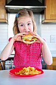A little girl eating a hamburger and fries