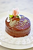 A birthday cake decorated with chocolate glaze and a marzipan rose