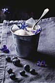 Vanilla ice cream with blueberries and sugared violets in a small metal cup
