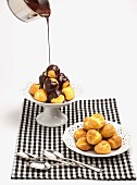 Chocolate sauce being poured over profiteroles