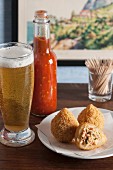 Coxinhas (fried chicken croquettes, Brazil) with a spicy sauce and a glass of beer