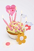A cupcake decorated with sugar hearts and candles for Valentine's Day