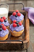 Cupcakes decorated with berry cream and fresh berries on a wooden tray