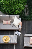 Blick von oben auf Holzterrasse mit hellgrauen Outdoor Polstermöbeln und Coffee-Table