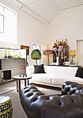 Black leather armchair, white sofa and African occasional furniture in spacious interior