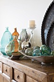 Dish of glass spheres and collection of glass vases on solid wooden cabinet