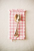 Two dessert spoons on a checked cloth
