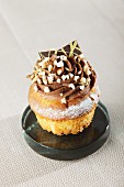 A cucpcake decorated with chocolate cream, nuts and chocolate sprinkles