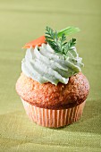 A carrot cupcake decorated with green cream