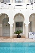 Arkadengang & Pool unter kreisförmiger Beleuchtung im Innenhof eines marrokanischen Hauses