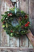 Festive wreath with berries and fire cones hanging on wooden door