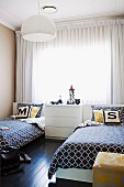 White chest of drawers flanked by twin beds with black and white patterned bedspreads