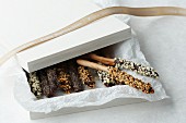 Decorated cinnamon sticks in a white box with tissue paper and a ribbon (Happy Christmas)