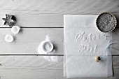 Baking tins, cutters, decorative pearls, a bauble and German words written on baking paper
