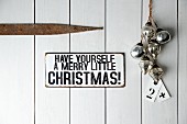 Sign (Have yourself a merry little Christmas) on wooden door next to baubles and tags