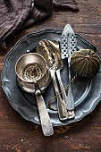 Silver kitchen utensils on a pewter plate and on a wooden surface