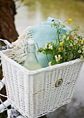 Drink, picnic blanket and bouquet of wild flowers in bicycle basket