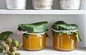 Jars of greengage jam with blackberry leaves wrapped around the lids