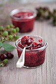 Raspberry and cranberry jam in a jar with a spoon
