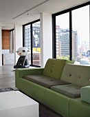 Polder sofa in shades of green and contemporary sculpture in background in front of continuous glass wall of loft apartment
