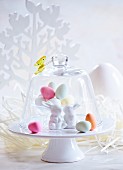 Colourful Easter eggs and Easter bunnies under a glass cloche
