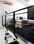 Blick durch schwarzes Galeriegeländer in Schlafbereich, selbstgebautes Bett auf schwarzem Teppich