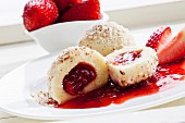 A quark dumpling with a strawberry filling and ground hazelnuts