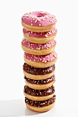 A stack of doughnuts with chocolate icing and pink icing