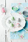 Five different cake pops on a plate with sugar pearls in the background