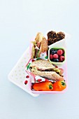 A lunch box with sandwiches, berries and peper