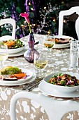 Appetisers, salads and white wine on a garden table