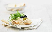 A slice of bread topped with chicken pate, olives and rocket