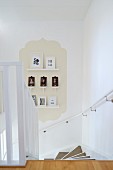 View down staircase with small gallery of framed pictures on beige panel in classic ogee shape