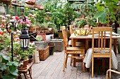 Wooden table and chairs in greenhouse with many planters on floor and stools