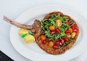 A breaded lamb chop with rocket and cocktail tomatoes