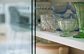 Various vintage glass vessels in glass-fronted cabinet