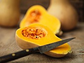 A butternut squash, halved, with a knife
