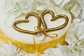 A wedding cake with two golden love hearts tied with a bow (close-up)