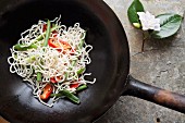 Raw vegetables, chilli peppers and noodles in a wok