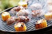 A smoking grill with corn cobs and meat