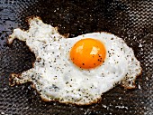 A fried egg with ground black pepper