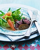 Roast beef with a mushroom sauce served with a green salad with beans and pomegranate