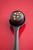 A chocolate praline with sugar decorations on a spoon