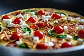 A breakfast omelette with tomatoes, feta cheese, ham and basil