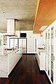 Moderne, weiße Küche mit freistehendem Mittelblock auf dunklem Dielenboden