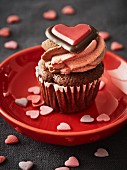 A chocolate cupcake topped with buttercream and decorated with a chocolate heart for Valentine's Day