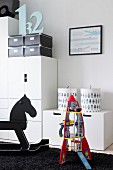 Modern, child's bedroom with robot and rocking horse in front of white, modern cupboard modules