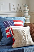 Kissen mit amerikanischer Flagge, auf teilweise sichtbarem Sofa, im Hintergrund Miniatur Leuchtturm